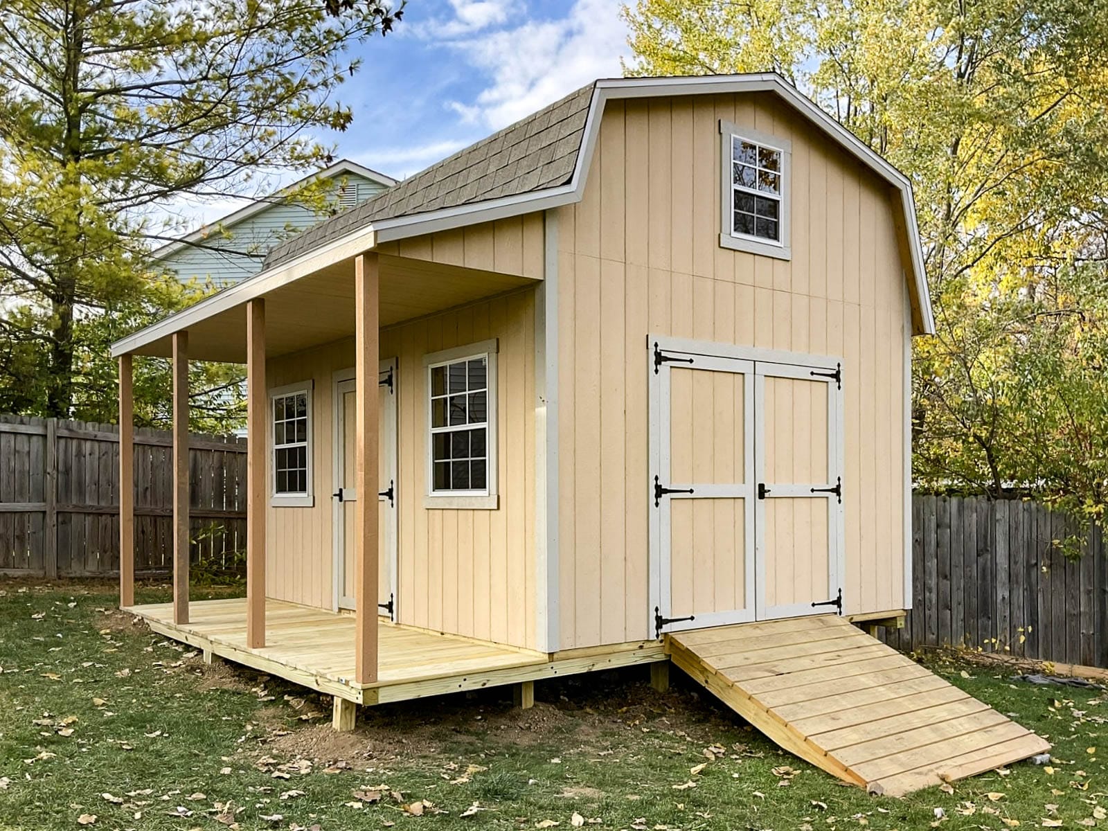 A peach barn-style shed with a beige trim, a ramp leading to the double doors, and a porch supported by wooden beams. Depending on your location, you may or may not need a shed permit in Ohio.