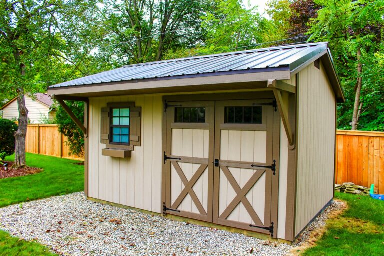 Tan Quaker-style shed with brown metal roof and decorative window trim.