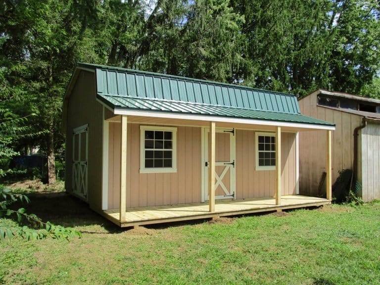 Tan shed with green trim and covered porch