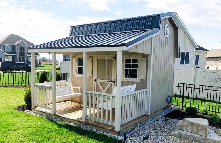 White retreat cabin with covered front porch, one of the sheds with porches for backyard living