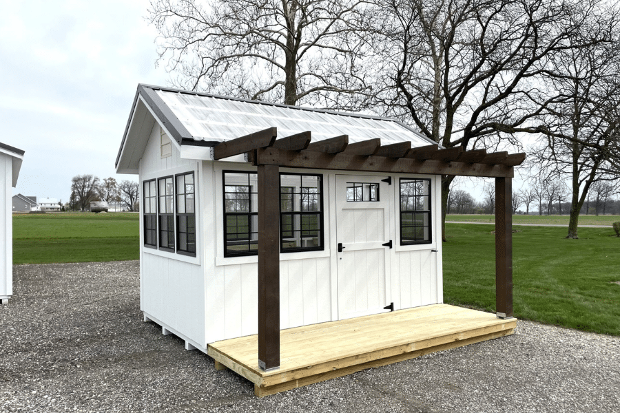 angle of left side of white and black trimmed green house with pergola style porch