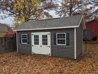 One of our gray and white Cape Cod sheds for sale in Lincoln Village OH - Gray siding with white double doors and white-trimmed windows with black shutters