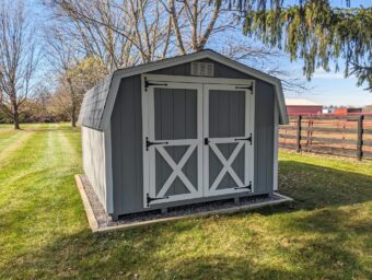 One of our gray and white mini barn sheds for sale in Lincoln Village OH - Gray siding with white-trimmed double doors below white vent and barn-style roof