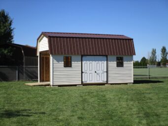 Wide view of one of our Highwall Garage sheds in Urbana OH - White siding with brown-trimmed white double doors between two brown-framed windows - open overhead door under brown metal roof - shed sits on green lawn along metal fence
