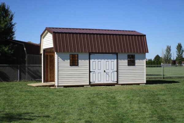 Wide view of one of our Highwall Garage sheds in Urbana OH - White siding with brown-trimmed white double doors between two brown-framed windows - open overhead door under brown metal roof - shed sits on green lawn along metal fence