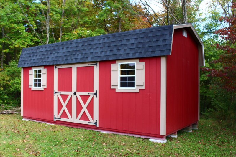 One of our Highwall sheds in Urbana OH - Red wood siding with beige-trimmed double doors and windows under black shingled roof