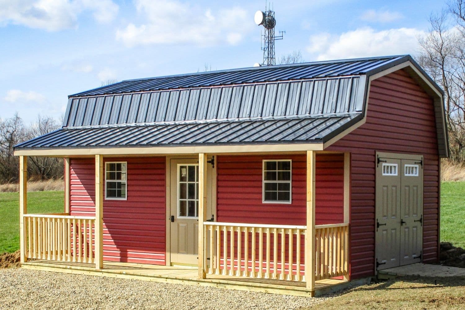 Red cabin-style shed with black metal roof and front porch.