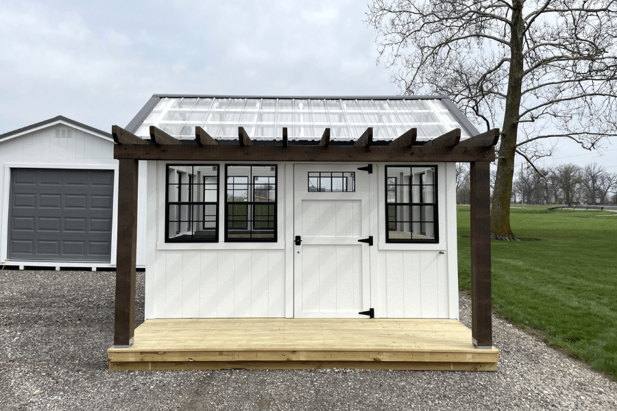 white greenhouse with black trim and pergola covered porch